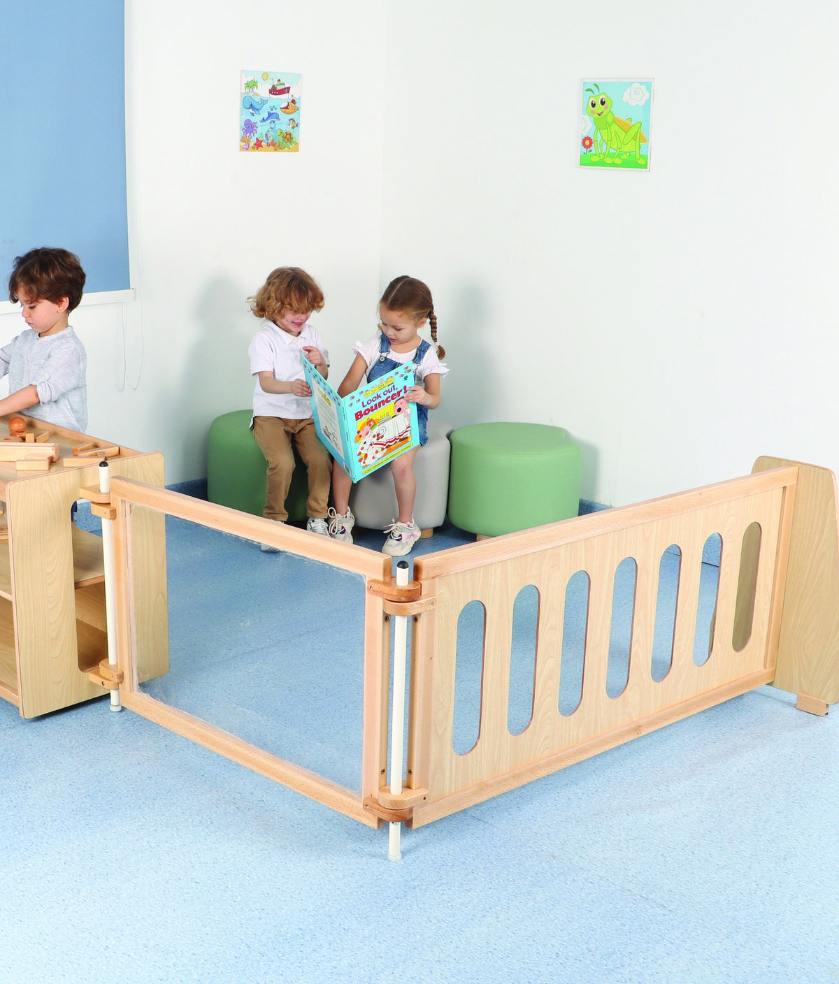 Children reading with an educator in a space framed by low wooden dividers.