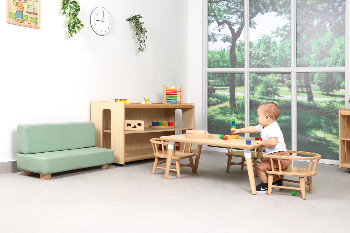 A toddler playing with wooden toys at a low timber table beside open shelving.