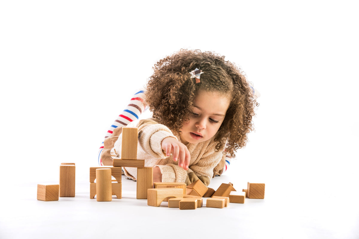 A young child building with natural wooden blocks