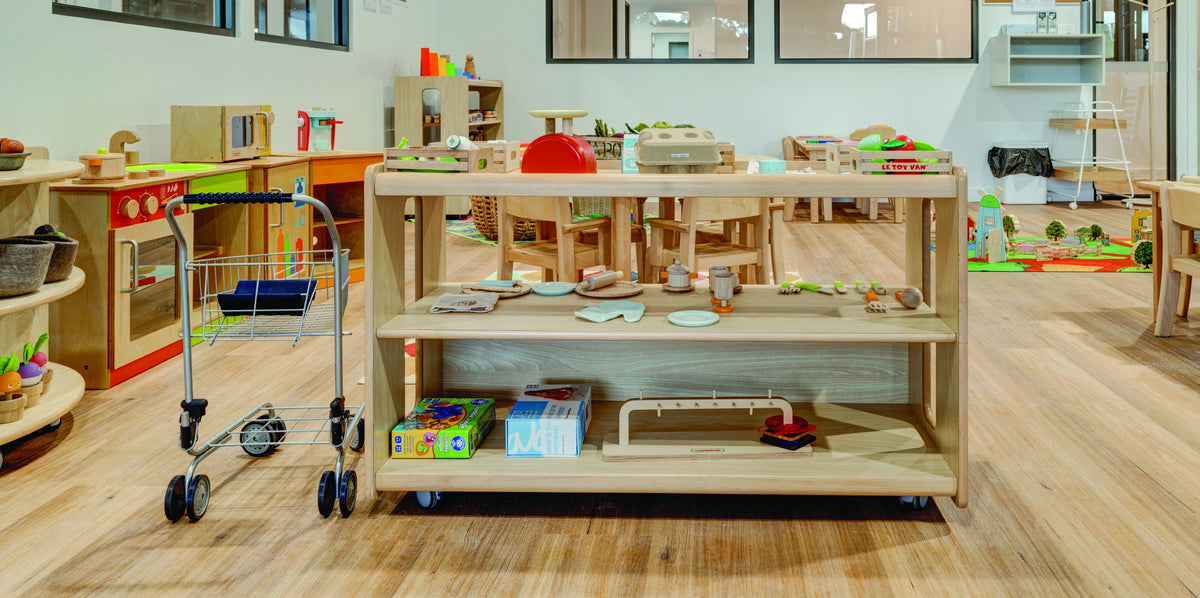 Mobile open shelves displaying learning resources in a furnished early learning room.