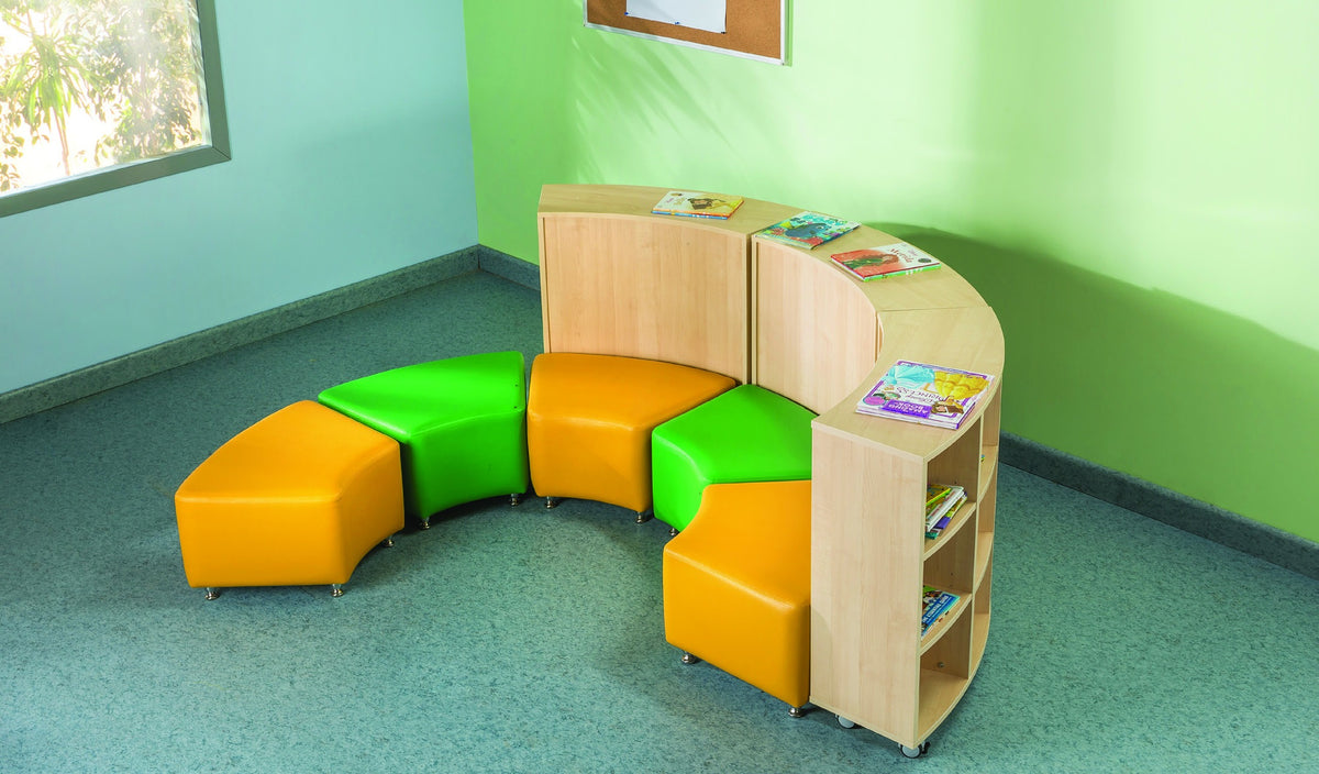 Curved wooden storage shelves and colourful soft stools form a reading nook.