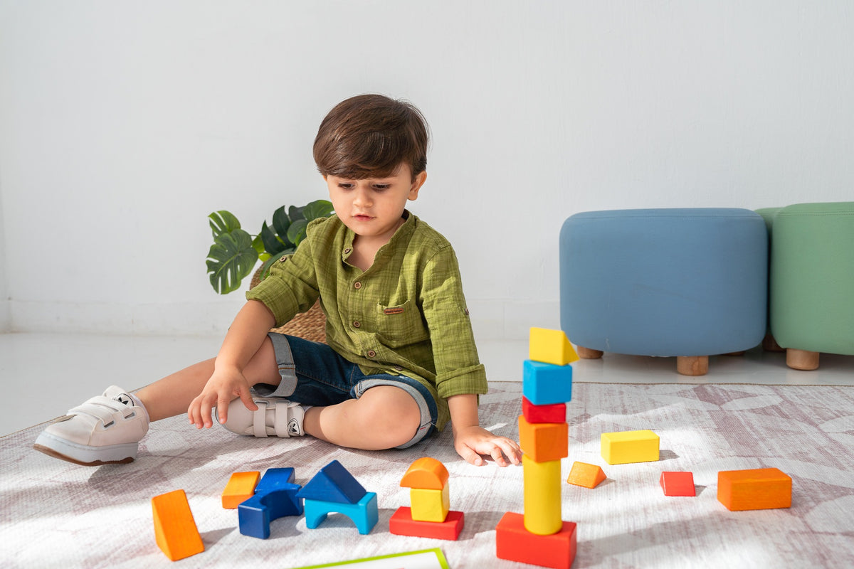 A child building with colourful wooden blocks on a rug.