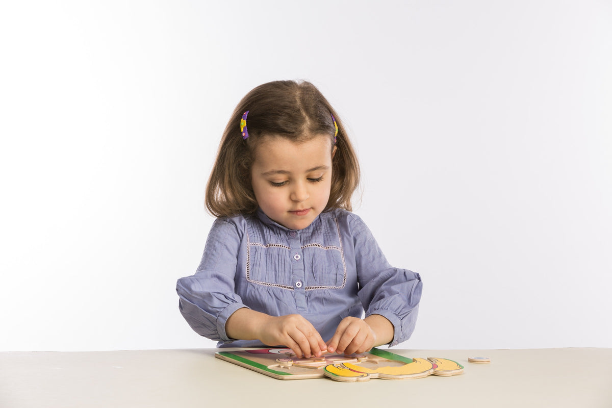 A child assembling a layered wooden figure puzzle.