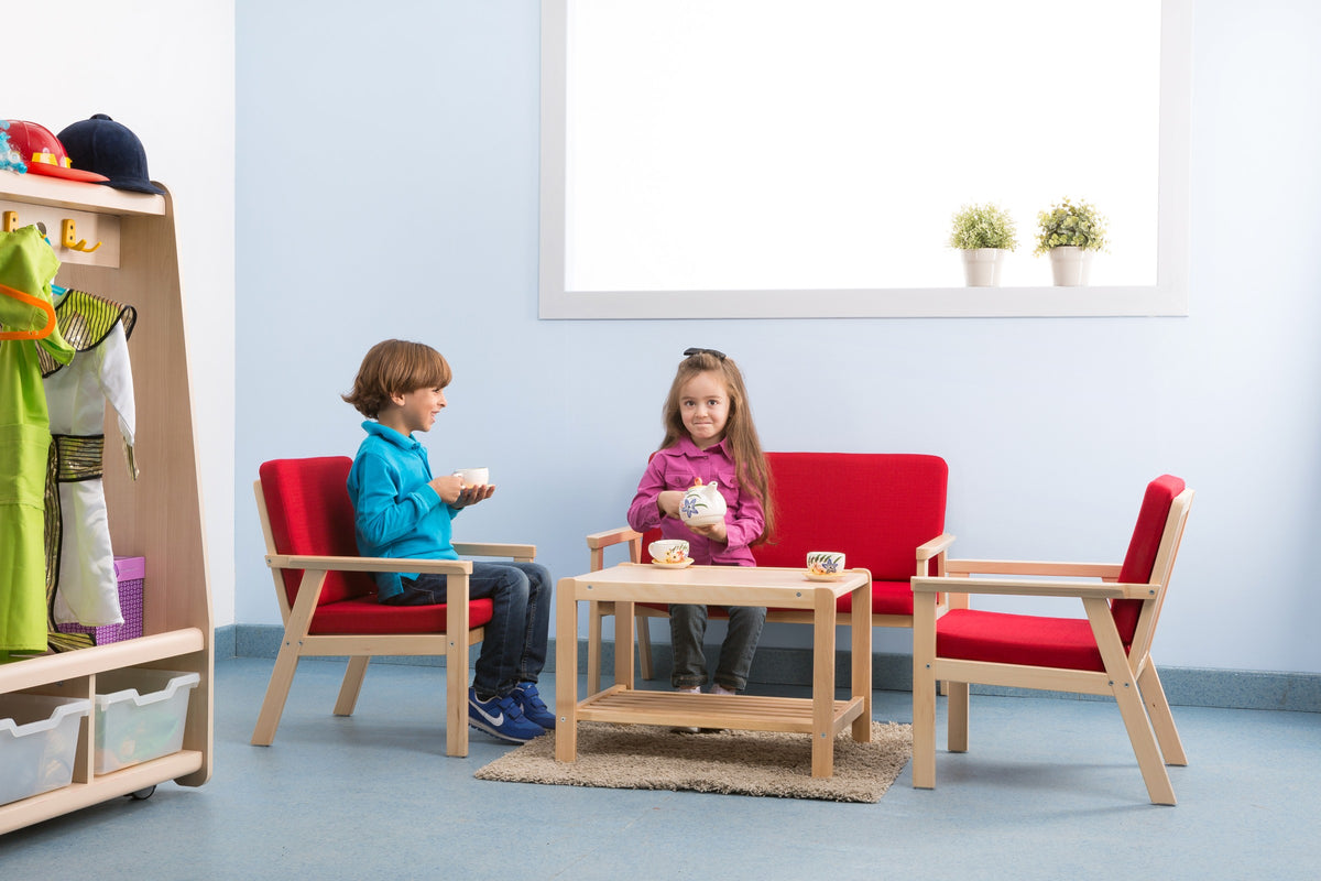Two children seated at a low table with a pretend tea set.