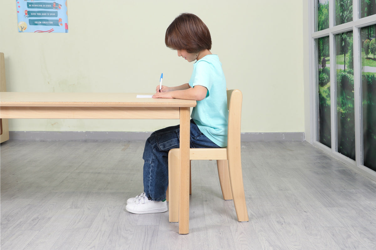 Side view of a child seated at a wooden table with feet flat on the floor