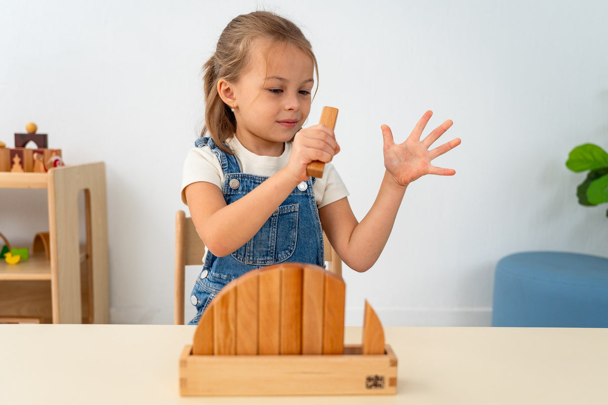 A child playing with natural wooden arches at a low table